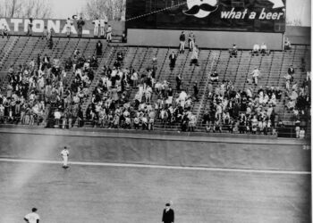 The ball kissed Mr. Boh's cheek as it soared over the left field bleachers. Young boys peer over the wall searching for the ball.